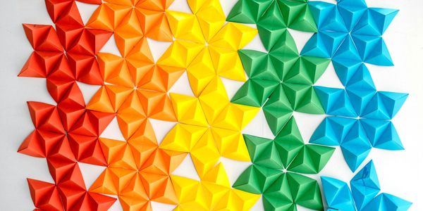 "Origami pattern in rainbow colors, symbolizing diversity, unity, and flourishing together."