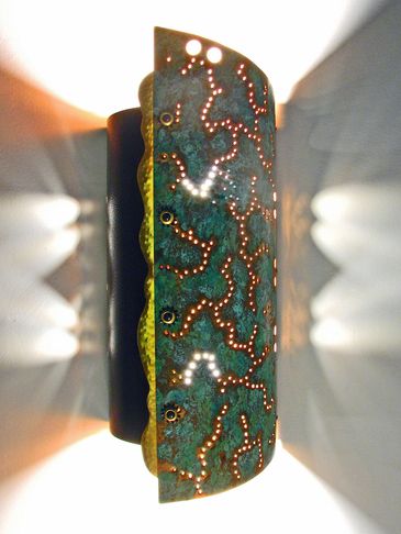 Decorative wall lamp with intricate perforated metal design casting artistic light patterns.