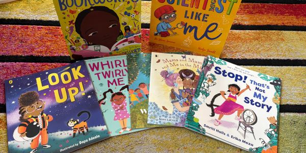 Colorful children's books with diverse characters displayed on a vibrant rug.