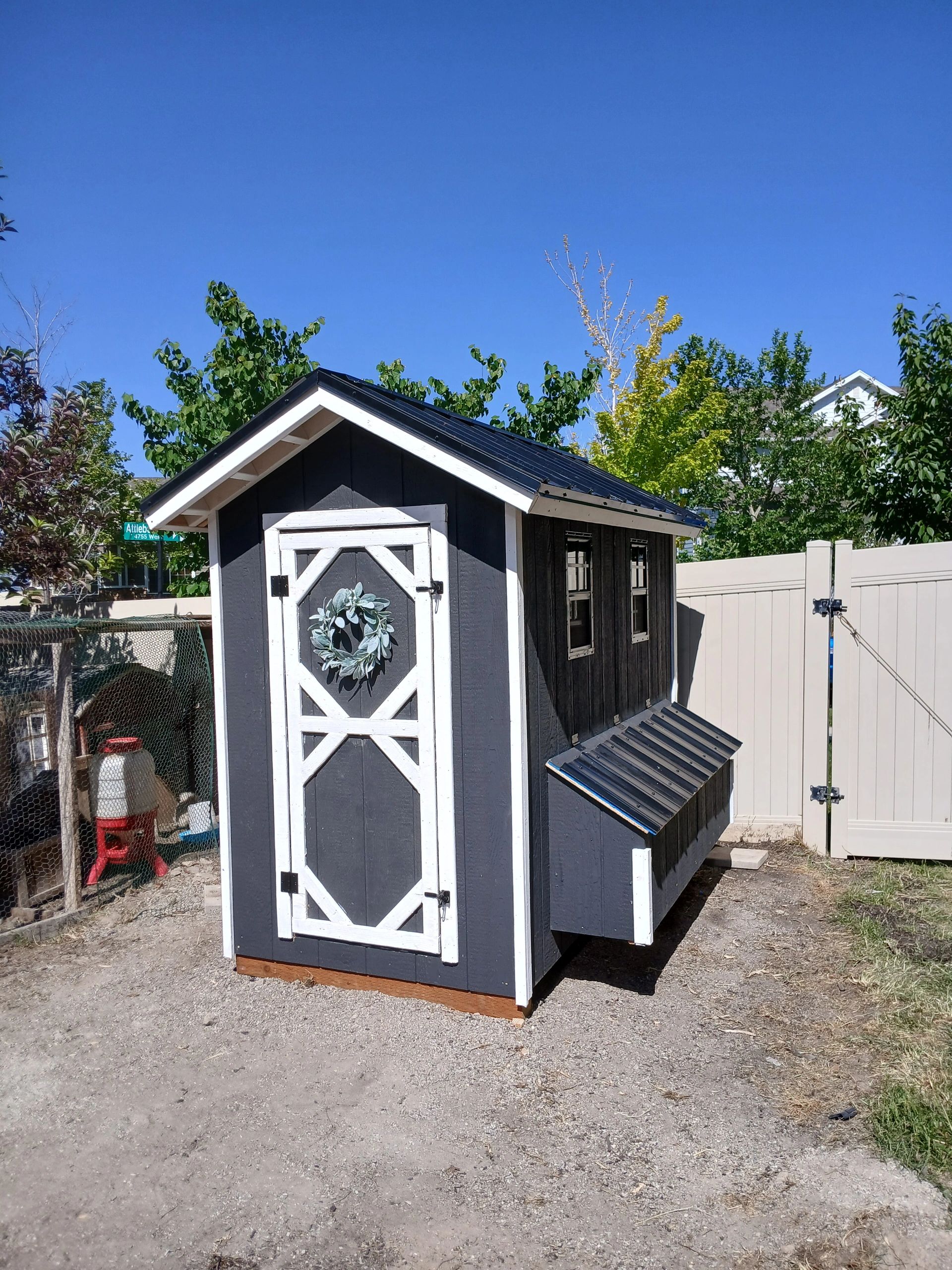 Small black and white backyard shed with a wreath on the door.