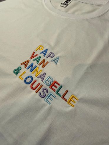 White t-shirt with colorful embroidered names.