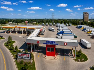 A busy truck center with parking and fueling station under blue skies.