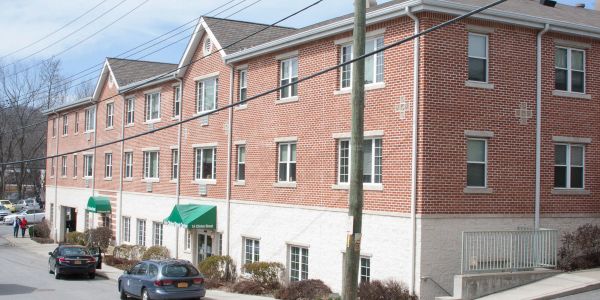 A brick and white three-story building with parked cars outside.