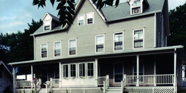 Large traditional house with gray siding and a spacious porch.