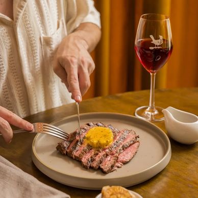 Guy eating a steak with glass of wine