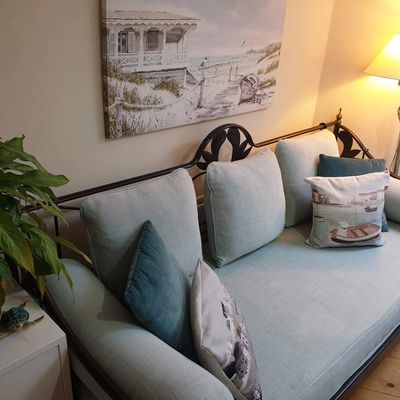 Therapy room with blue sofa, plant, beach picture and lamp
