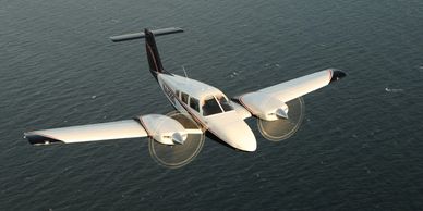 A twin-engine airplane flying over the ocean with propellers spinning.