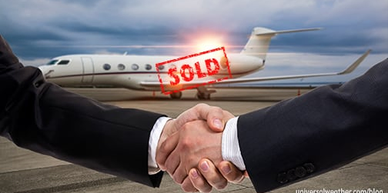 Two people shaking hands in front of a sold private jet.