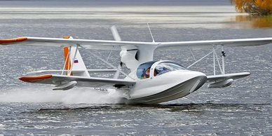 A white amphibious aircraft gliding over water.