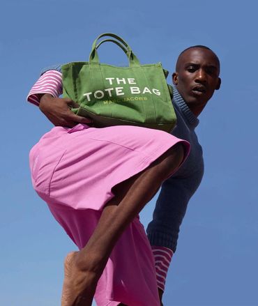 Model showcasing a green Marc Jacobs tote bag against a clear blue sky.