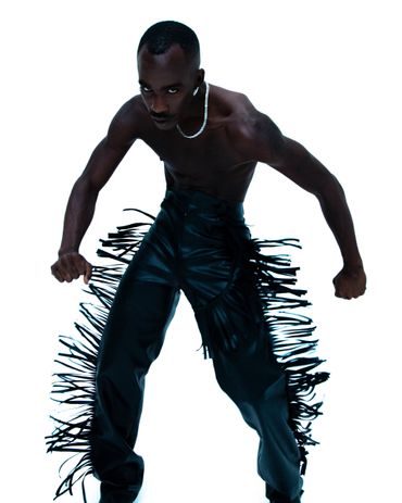 Man in black leather fringe pants striking a powerful pose.