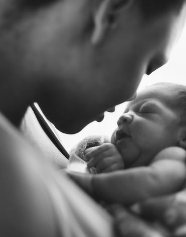 A closeup image of a mothers profile as she nuzzles in close to her newborn during a photo session, 