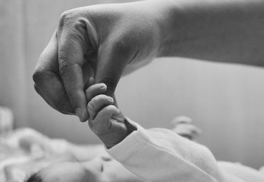 A mother's hand holding her newborns hand during a newborn photo session. 