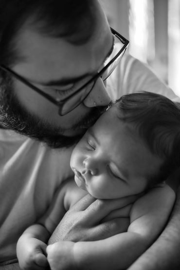 Father kissing newborn son during lifestyle session with capturedbyceleste.com in Kingsport. 