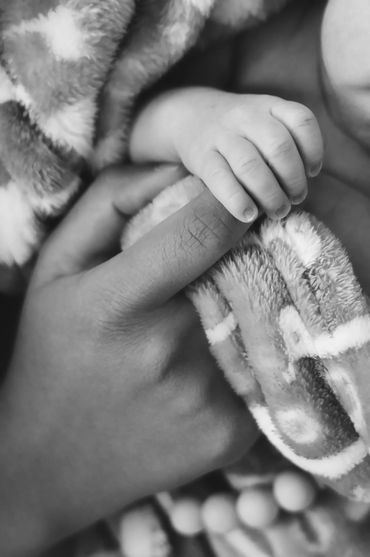 black & white close up image of a mother holding her newborns tiny fingers during a photo session. 