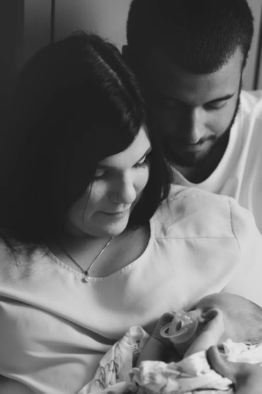 black & white photo of a couple with their newborn 