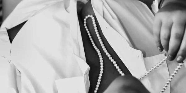  woman  touching her pearl necklace while lying on bed, Black and white boudoir photo. 