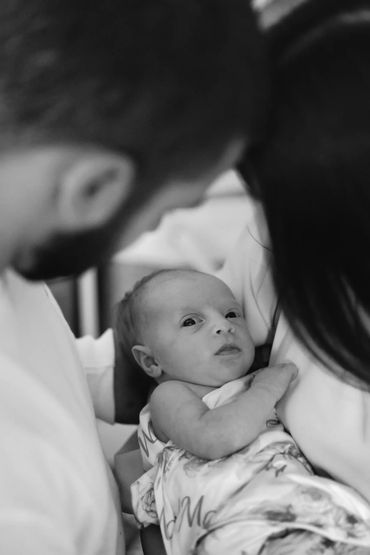 black & white photo of couple holding newborn close.