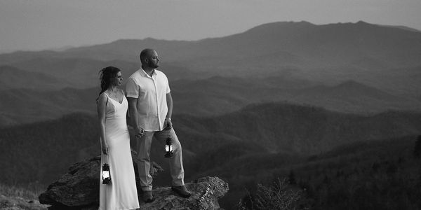 Bride and groom holding lanterns at dusk overlooking the Appalachian Mountains during their Roan Mou