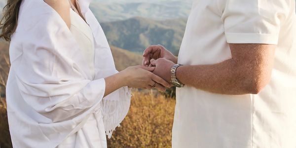 Bride and groom exchanging rings with the Appalachian Mountains behind them during their Roan Mounta