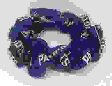 A blue scrunchie with the new england patriots logo on it placed on an all white scrunchie.
