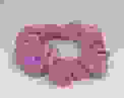 A pink handmade scrunchie placed on an all white background.
