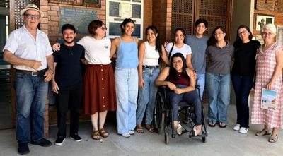 A diverse group of people smiling together outside a building.