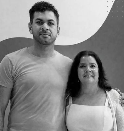 A man and woman posing together in front of a patterned wall.