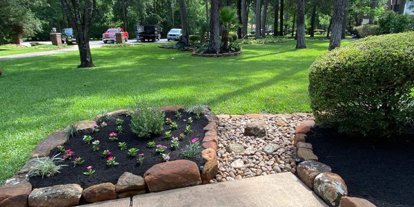 Well-maintained garden with flowerbed and rock path.