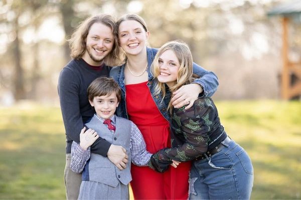 A happy family of four embracing outdoors on a sunny day.