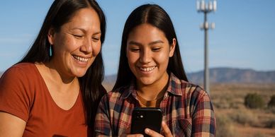 Two women happily looking at a phone outdoors.