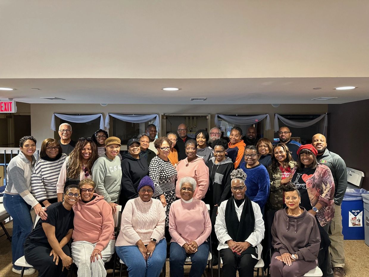 Large group of diverse adults posing indoors for a group photo.