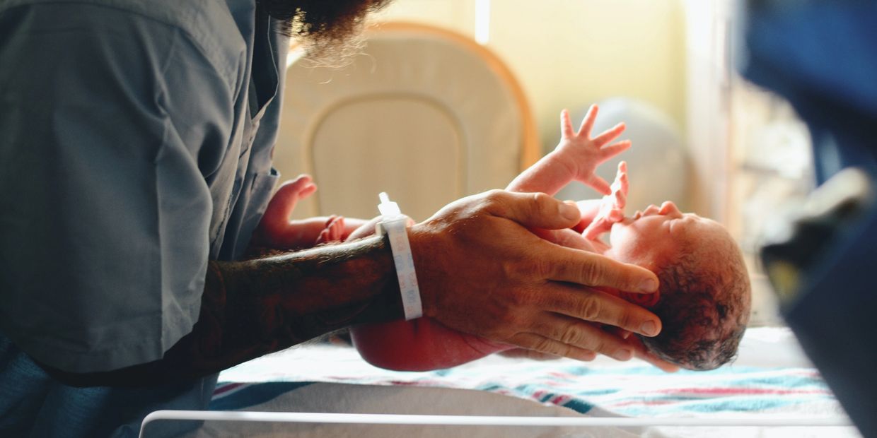 Man lifting baby off infant hospital scale. 