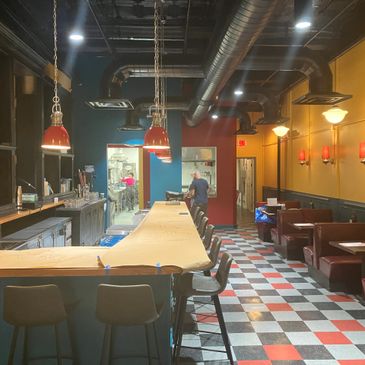 Empty bar with red and black checkered floor and hanging lights.