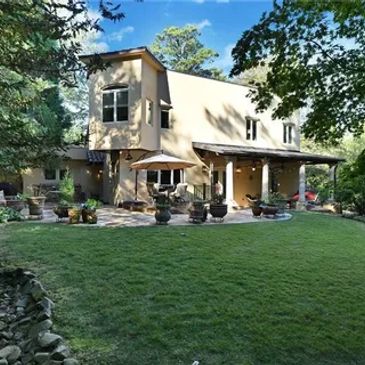Modern two-story house with a spacious backyard and patio area.
