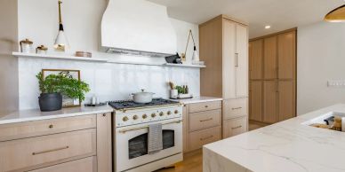 Modern kitchen with light wood cabinets and white countertops.
