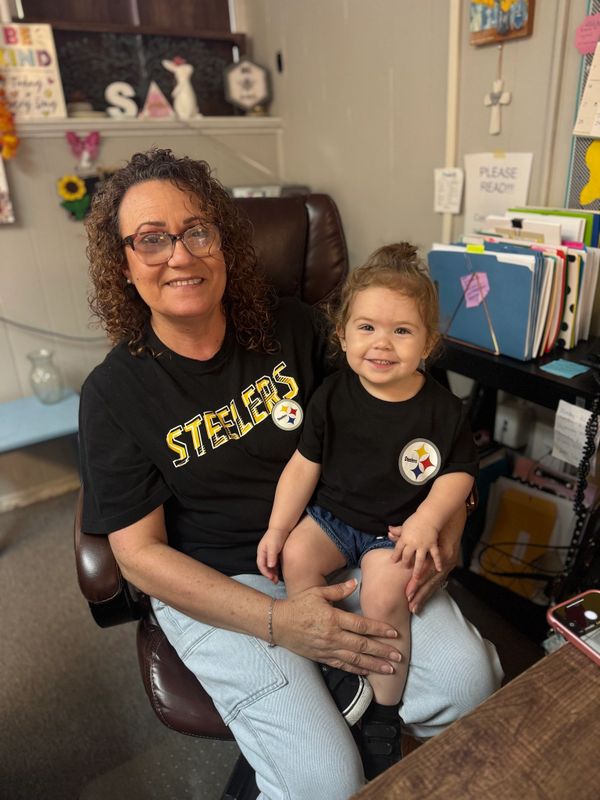 Woman and child wearing matching Steelers shirts, smiling indoors.