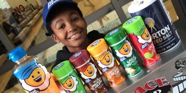 Smiling boy with a variety of colorful spice containers and a salt canister.