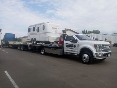 Flatbed truck towing a camper that was broken down