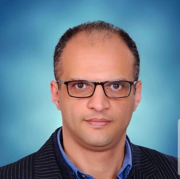 Man wearing glasses and a suit against a blue background.