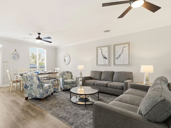 Modern living room with gray sofas, patterned chairs, and ceiling fans.