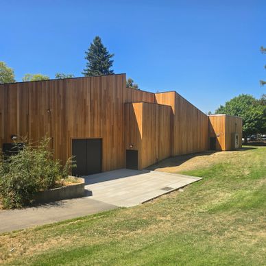 Modern wooden building with geometric design under clear blue sky.