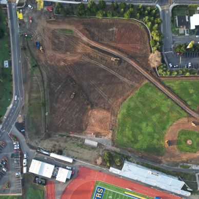 Aerial view of a construction site next to a sports field and track.