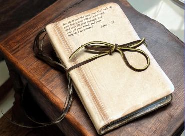 Leather-bound book with a scripture quote tied with a leather string.