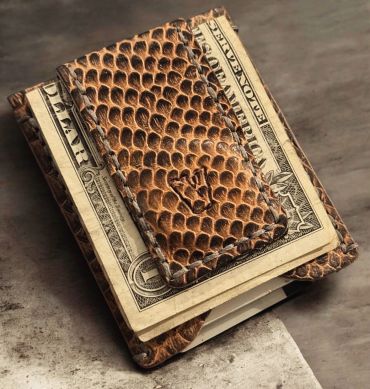 A textured leather money clip holding folded dollar bills.