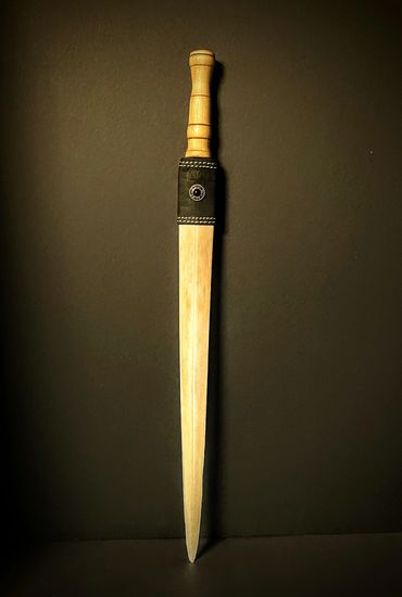 Wooden practice sword with a leather guard on a dark background.