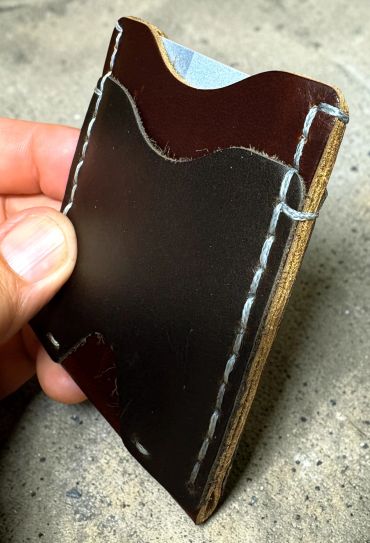 Handcrafted brown leather card holder with white stitching.