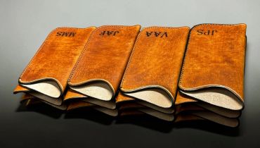 Four leather pouch cases with initials on each.
