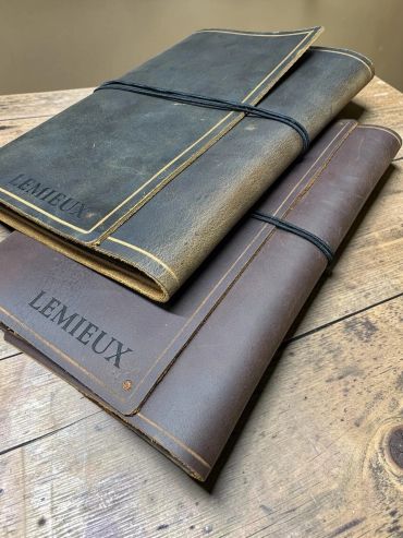 Two leather-bound Lemieux folders on a wooden surface.
