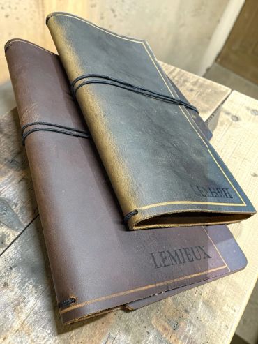 Two leather-bound notebooks with elastic bands on a wooden surface.